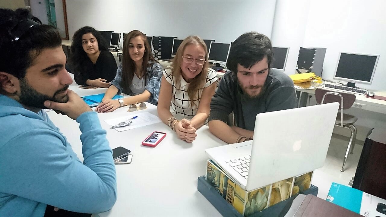 Students and a teacher at the American University of Technology in Lebanon interacting with students in New York through their laptop.