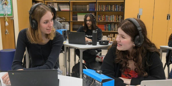 Three students sitting in a classroom - Eleanor, Mizael, and Alina
