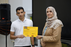 Raad holding a certificate presented by the teacher Ms. Amal