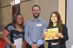 three people standing together for a photo, one holding a certificate