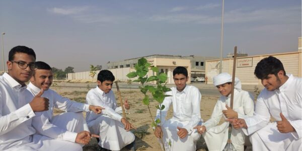 A group of students next to a seedling