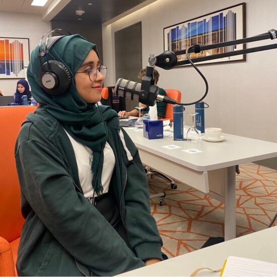 Young woman in front of a podcasting microphone.