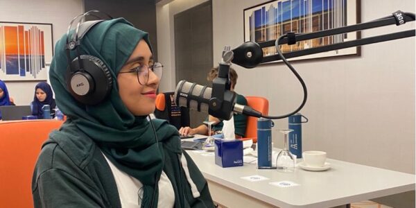 Young woman in front of a podcasting microphone.