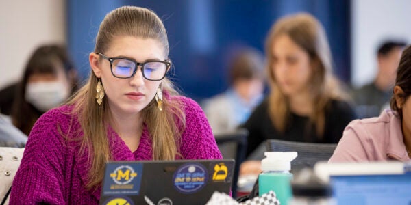 A girl sitting at a desk looking at her laptop.